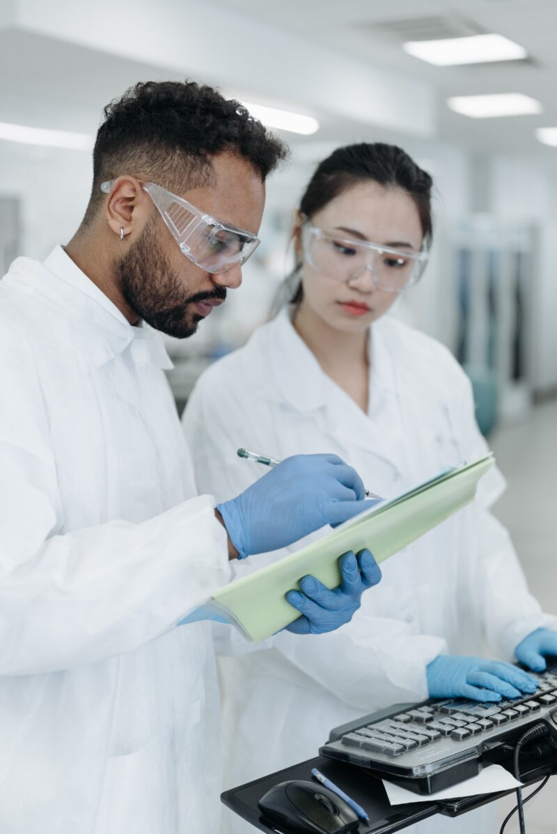 Male and female laboratory researchers writing on a table solving problems related to patient antibodies, blood typing, antigens, and much more.