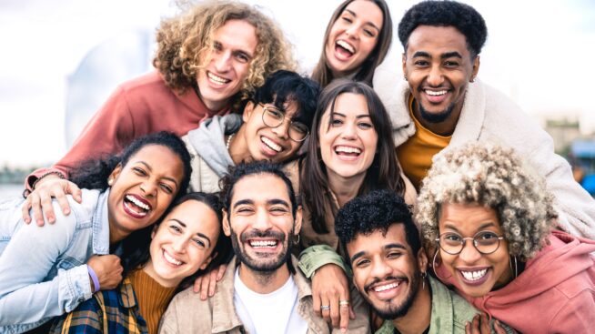 Multi-ethnic group of smiling and laughing young men and women taking a selfie outdoors