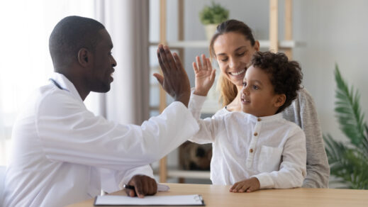 Doctor giving a high five to a child sitting on his mother's lap