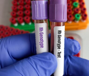 Gloved hand of lab technician holding vial of blood