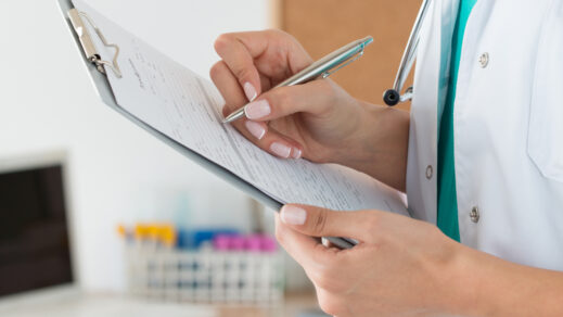 Image of female with pen in hand completing lab form on notepad