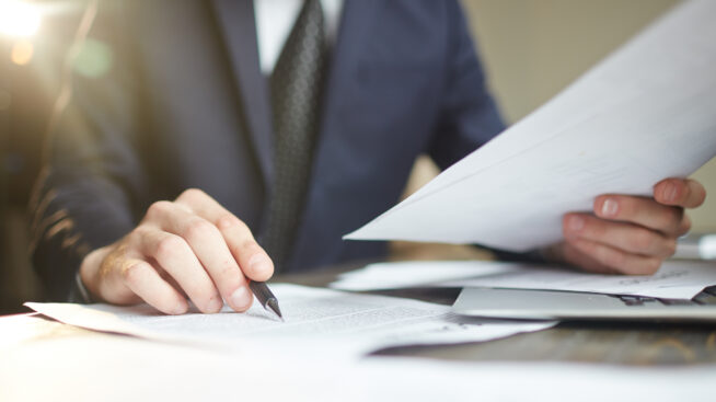 Person in a suite at a desk filling out paperwork