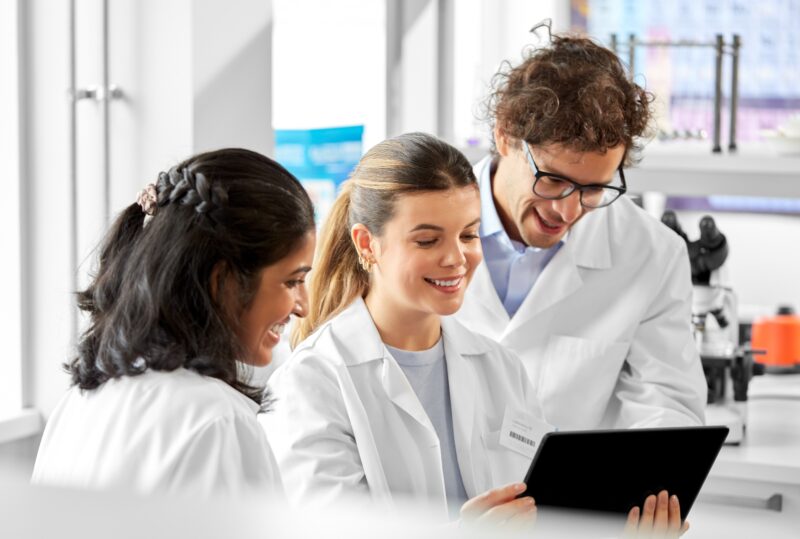 Three lab technicians smiling over a laptop