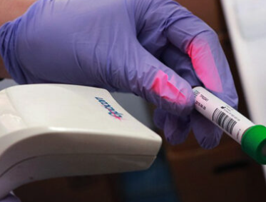 New York Blood Center laboratory technician holding marked vial of blood